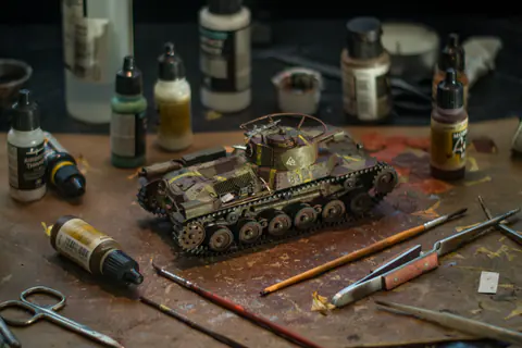 Maquette de char peinte entourée de peintures et de pinceaux